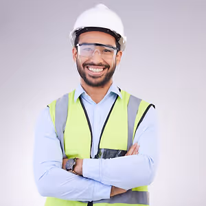 A man in a white helmet and green vest is smiling and posing for a photo.