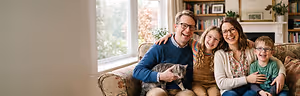 A smiling family of four with a cat sitting on the man's lap