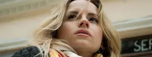 Blonde woman wearing scarf and looking upwards outside of building