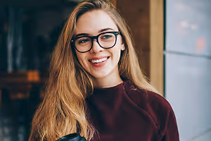 Woman with glasses and a maroon top smiling at the camera