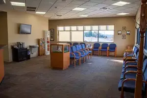 A waiting room with blue chairs and a television on the wall.