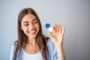 Woman holding a contact lens container and smiling