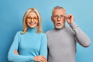 A man and a woman wearing glasses and smiling for the camera