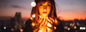 Woman holding glowing lights in her hands against a cityscape background
