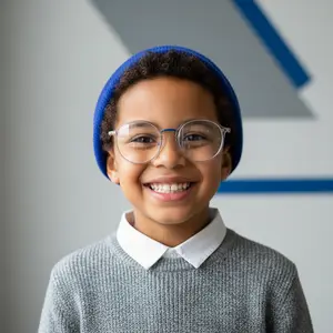 young boy with glasses and a knit hat smiling at the camera