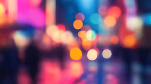 A blurry image of a city at night with people walking and colorful lights