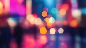 A blurry image of a city at night with people walking and colorful lights