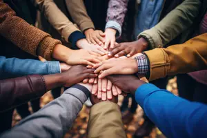 A group of people holding hands in a circle, with a focus on their unity and connection.