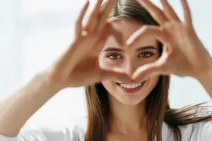 woman making a heart shape with her hands in front of her face