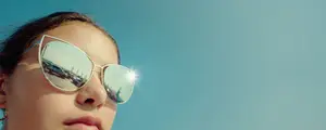 A woman wearing sunglasses and looking at the sky