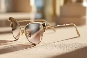Close up of gold-framed sunglasses with reflective lenses resting on a beige surface