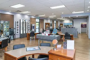 Interior view of an optometrist's office with tables, chairs, mirrors, and display cases.
