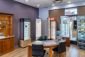 A room with many display cases for glasses, a desk with chairs, and a surveillance camera on the ceiling.