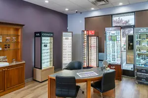A room with many display cases for glasses, a desk with chairs, and a surveillance camera on the ceiling.