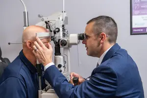 An adult male is getting his eyes checked by an optometrist at an eye clinic