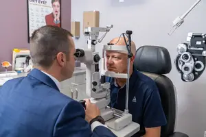 An optician examines a patient's eye using an ophthalmoscope in a clinic setting.