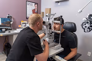 Man looking through eye exam machine in an optometrist office