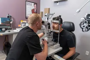 Man looking through eye exam machine in an optometrist office