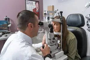 An eye doctor examining a patient with a slit lamp in an eye clinic.