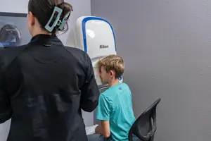 A young boy is having his eyes examined by an eye doctor using a Nikon device.