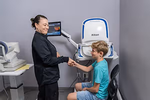 A woman shakes hands with a boy in a medical setting