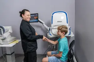 A woman shakes hands with a boy in a medical setting