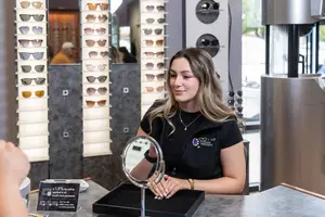 A woman with blonde hair sitting in front of a table with a mirror and a sign that says 4.15% fee will be applied to all credit card payments.