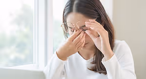 Closeup of a woman sitting at a desk and adjusting her glasses