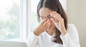 Closeup of a woman sitting at a desk and adjusting her glasses