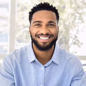 A man wearing a blue shirt and smiling for a photo