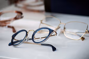 Three pairs of eyeglasses with different colored lenses and frames displayed on a white surface.