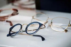 Three pairs of eyeglasses with different colored lenses and frames displayed on a white surface.