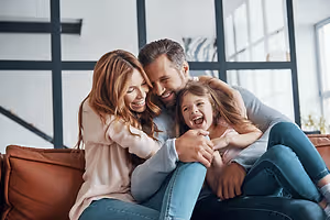 A family sitting on a couch and smiling for the camera