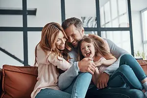 A family sitting on a couch and smiling for the camera