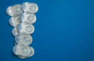 A stack of transparent medical contact lenses on a blue background