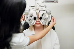 Woman sitting in a chair while another woman holds a device over her eyes