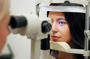 A woman in a room getting her eyes checked by a doctor.