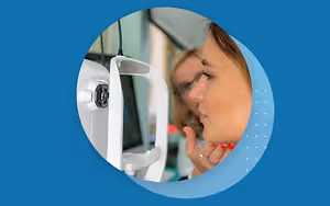 woman in optical shop looking at monitor with finger on eye