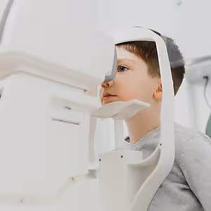 A young boy is getting his eyes examined by an eye doctor with a special eye examination machine