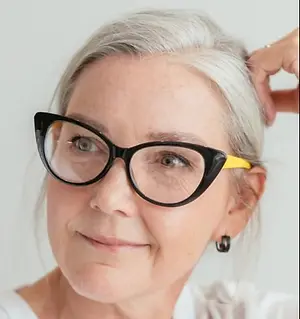 Close up of a woman smiling while adjusting her glasses