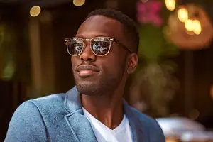 A man in a blue jacket and white shirt is posing for a picture outside