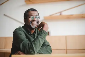 A man with glasses smiling while posing for a photograph inside a restaurant