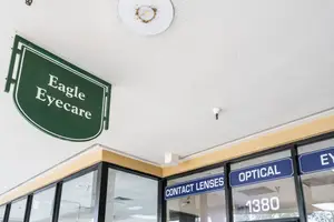 The exterior of the Eagle Eyecare establishment features a green sign and glass doors with blue signs.