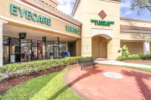 The front entrance of the Eyecare and Dentist building with a bench in front of it
