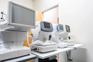 Medical equipment including monitors and eye testing machines are arranged on a table inside a room