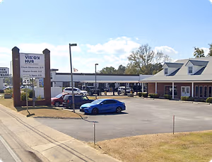 A photo of a road with cars parked in front of a building called The Vision Hub