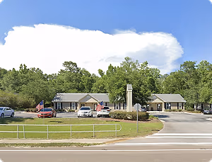 A building with two flags in front of it and cars parked in front of it.