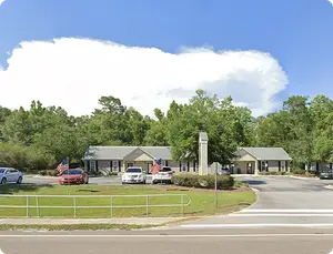 A building with two flags in front of it and cars parked in front of it.