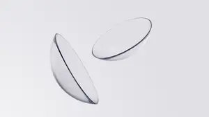Two clear contact lenses with blue rims placed on a white surface