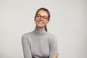A smiling woman wearing glasses and a turtleneck poses for a photo